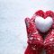 Женски ръце в плетени ръкавици със снежно сърце на снежен фон